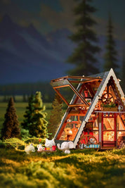 Miniature model of a A-Frame cabin in a forest with glowing interior lights