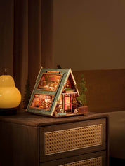 Wooden A-Frame Cabin Model with lights on a nightstand with a warm glow.