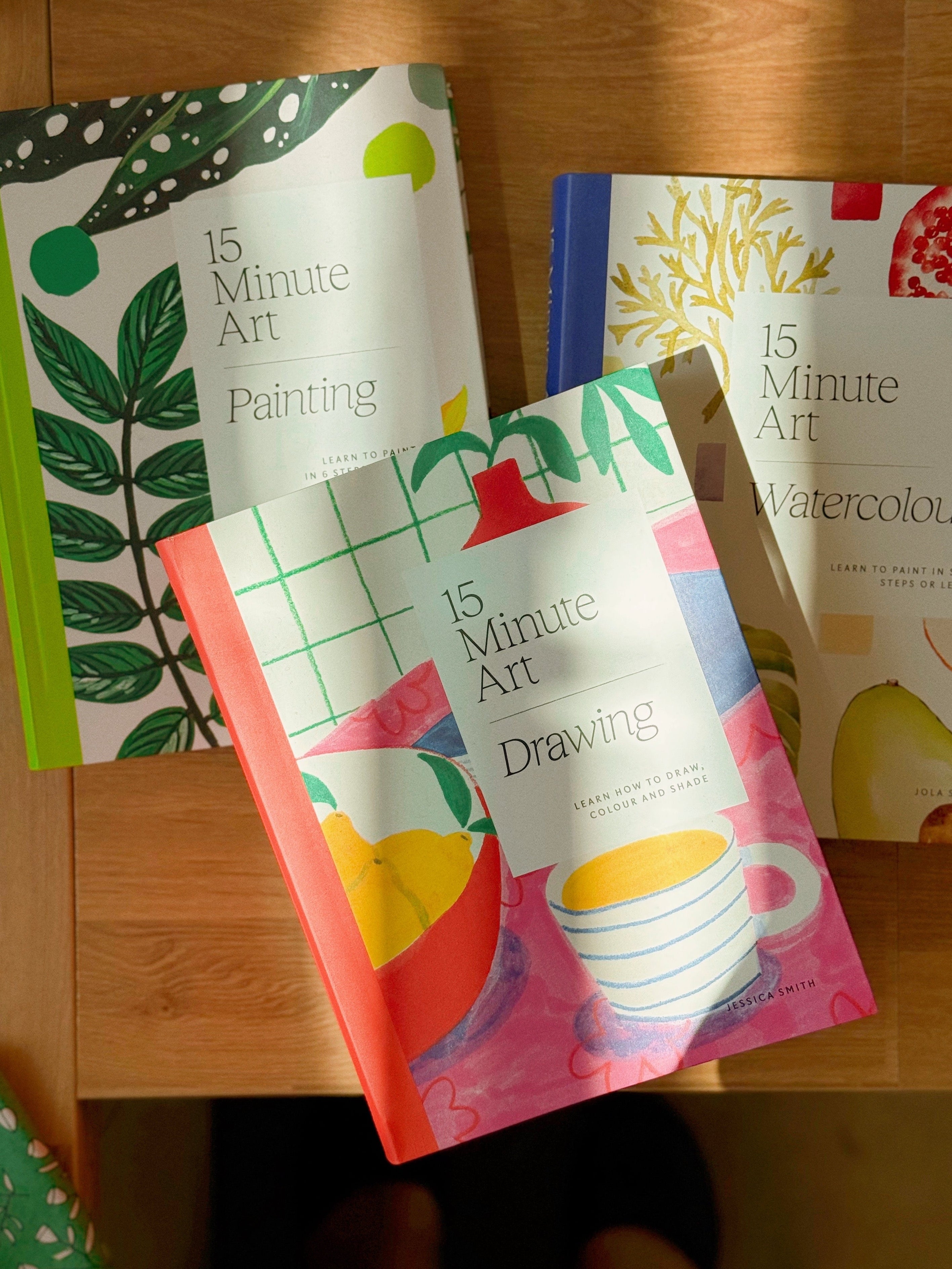 Three books titled '15 Minute Art Painting', '15 Minute Art Drawing', and '15 Minute Art Watercolour' on a wooden surface.