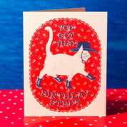 Birthday card with a cat illustration and text on a blue and red background