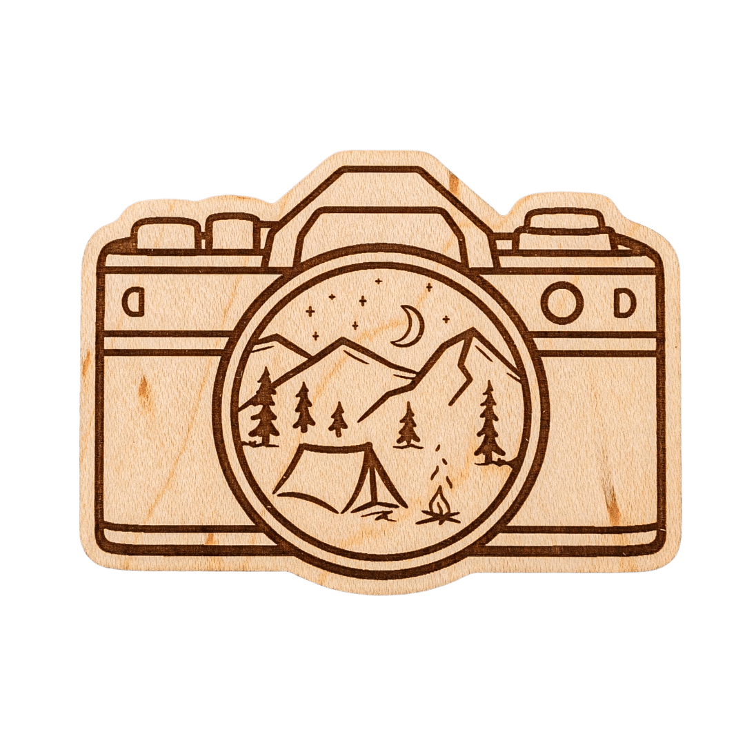 Wooden camera-shaped magnet with mountain and tent design on the lens.