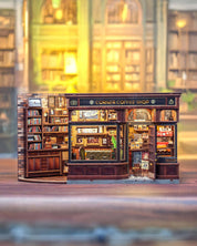 Model of a corner coffee shop with detailed interior, including books and furniture, on a blurred background.