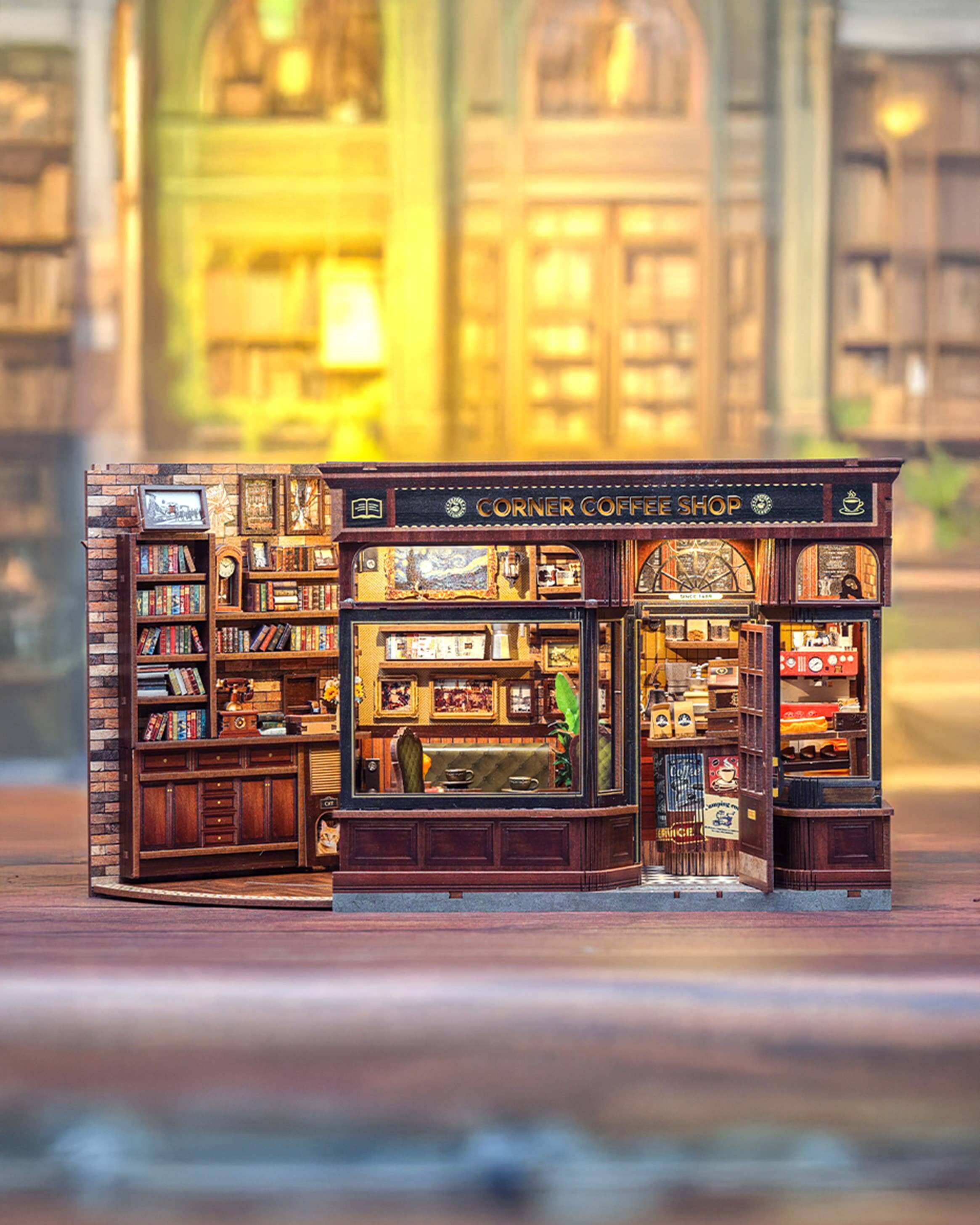 Model of a corner coffee shop with detailed interior, including books and furniture, on a blurred background.
