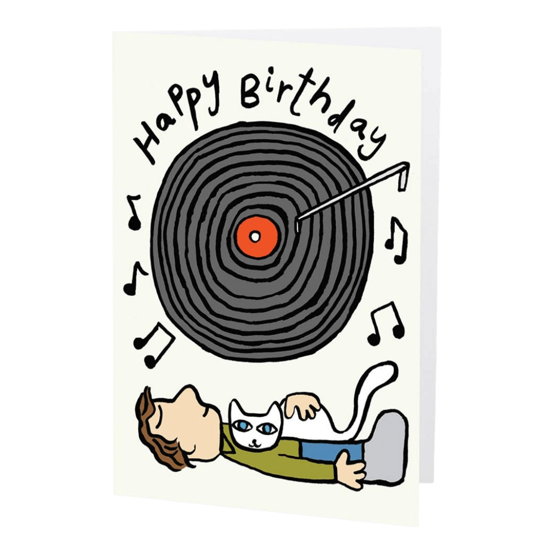 Birthday card with a record player and person lying down with a cat, featuring musical notes and 'Happy Birthday' text.