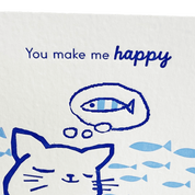 Cartoon cat with thought bubble containing a fish, surrounded by more fish, on a white background with 'You make me happy' text.