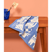 Blue towel with white pattern draped over a wooden surface against a peach background