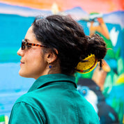 Woman with sunglasses and bun wearing wearing a hair claw clip shaped like a taco with visible fillings.