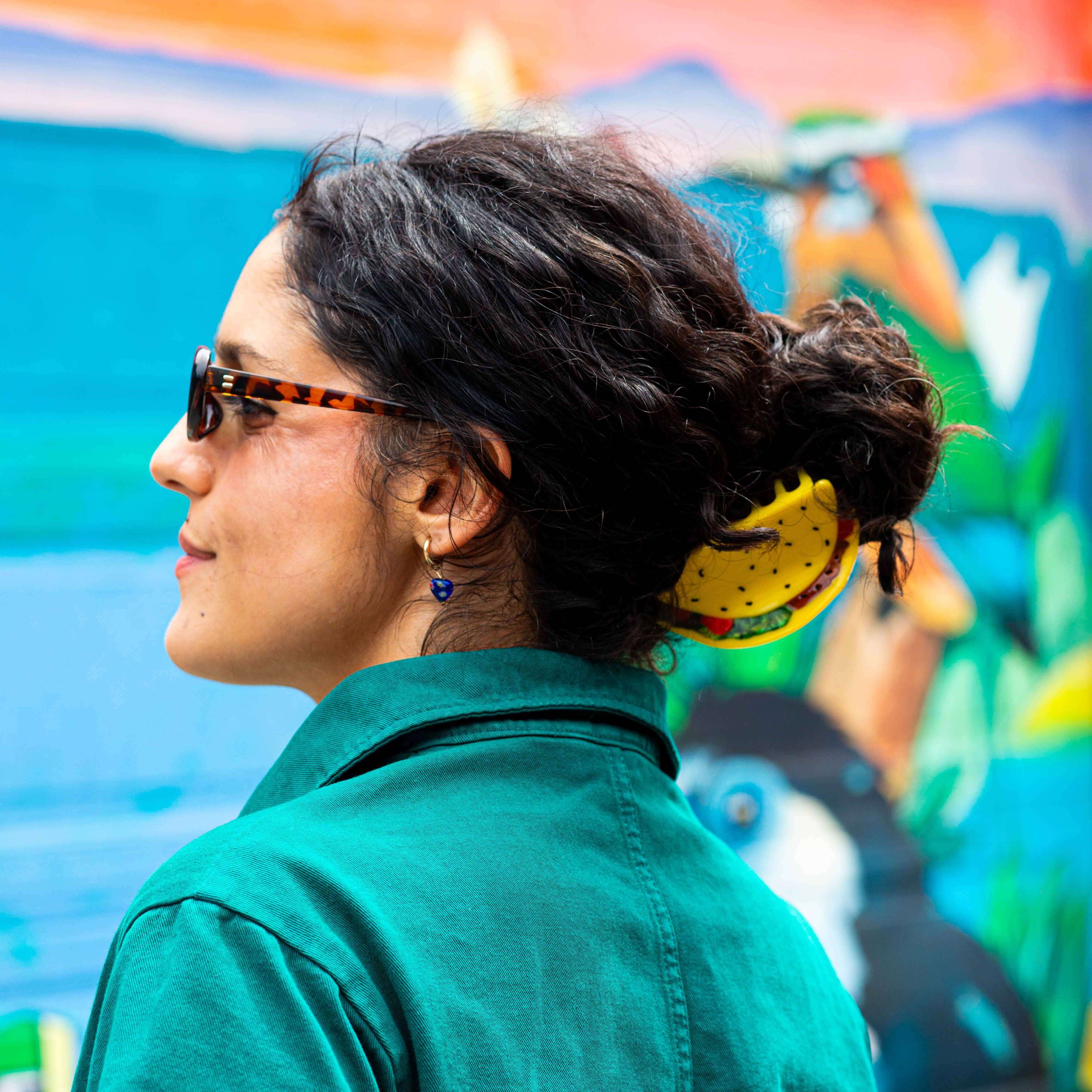 Woman with sunglasses and bun wearing wearing a hair claw clip shaped like a taco with visible fillings.
