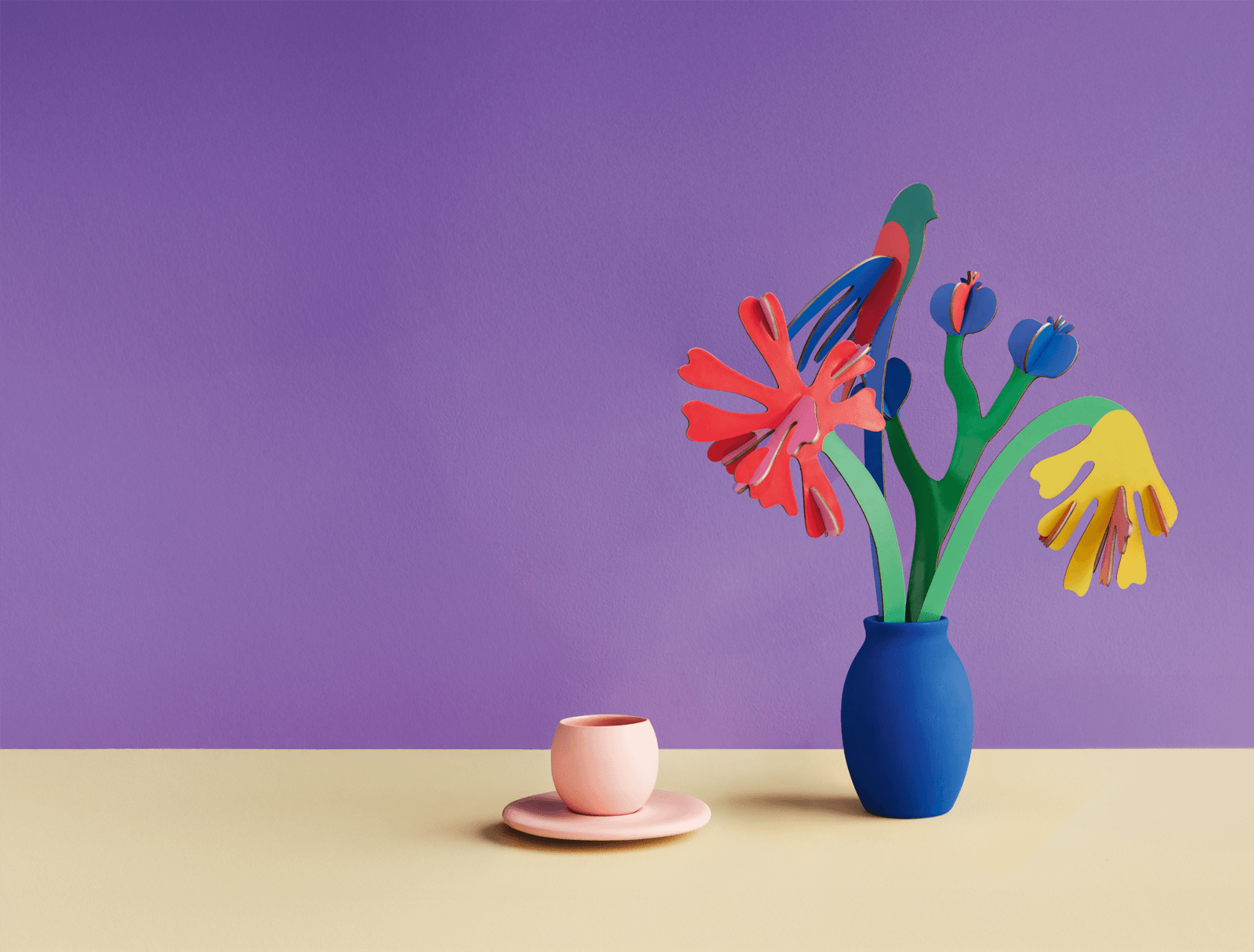 Colorful cardboard flowers in a blue vase on a purple background