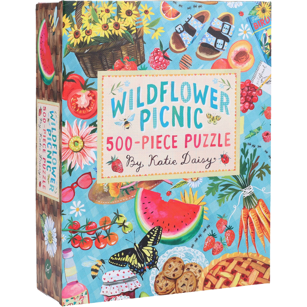 Box of 'Wildflower Picnic' 500-piece puzzle by Katie Daisy with colorful illustrations of picnic details on a blue background.