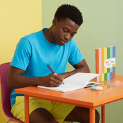 Person sitting at a table with a notebook and pen, against a colorful background