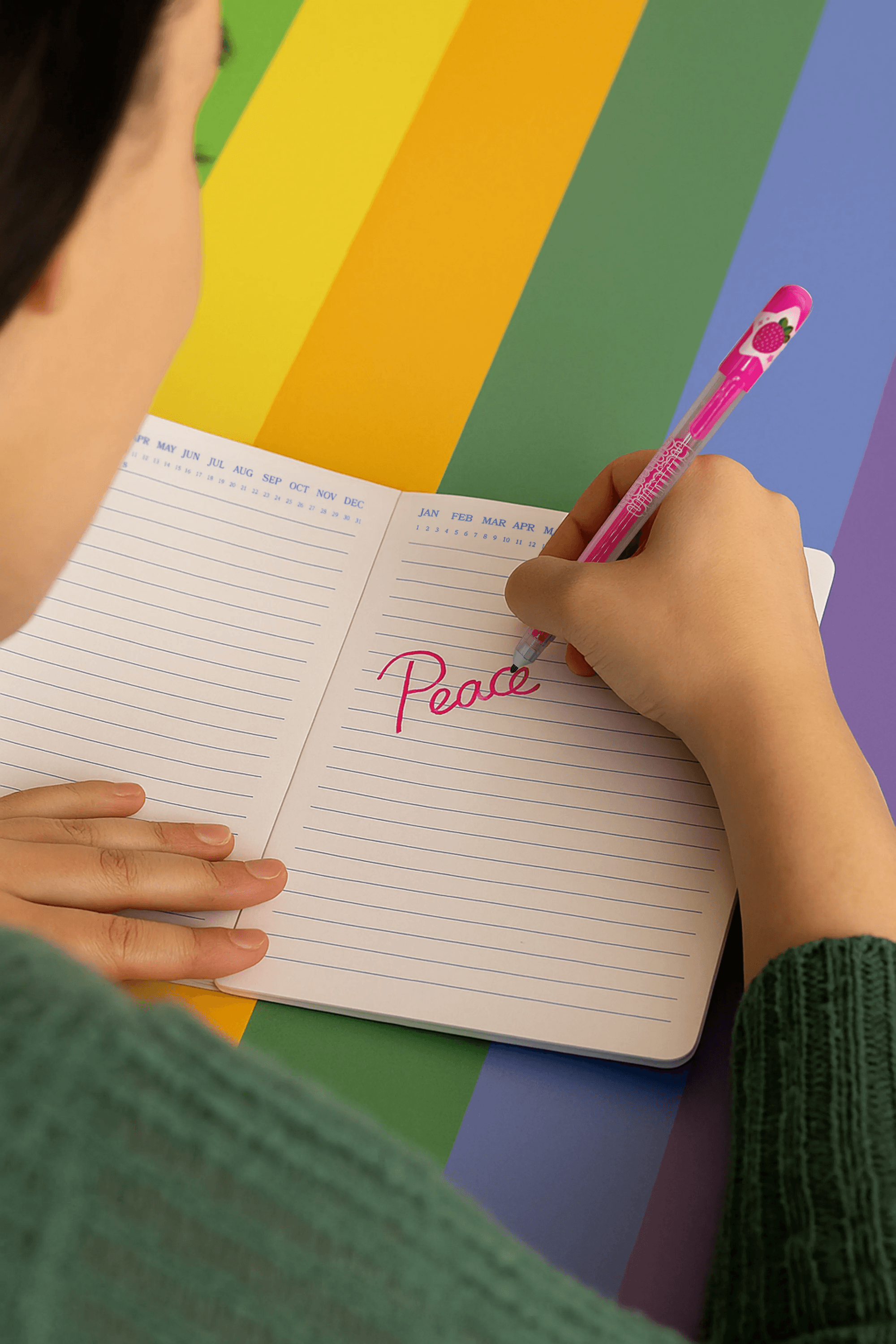Person writing 'Peace' in a notebook with a colorful striped background