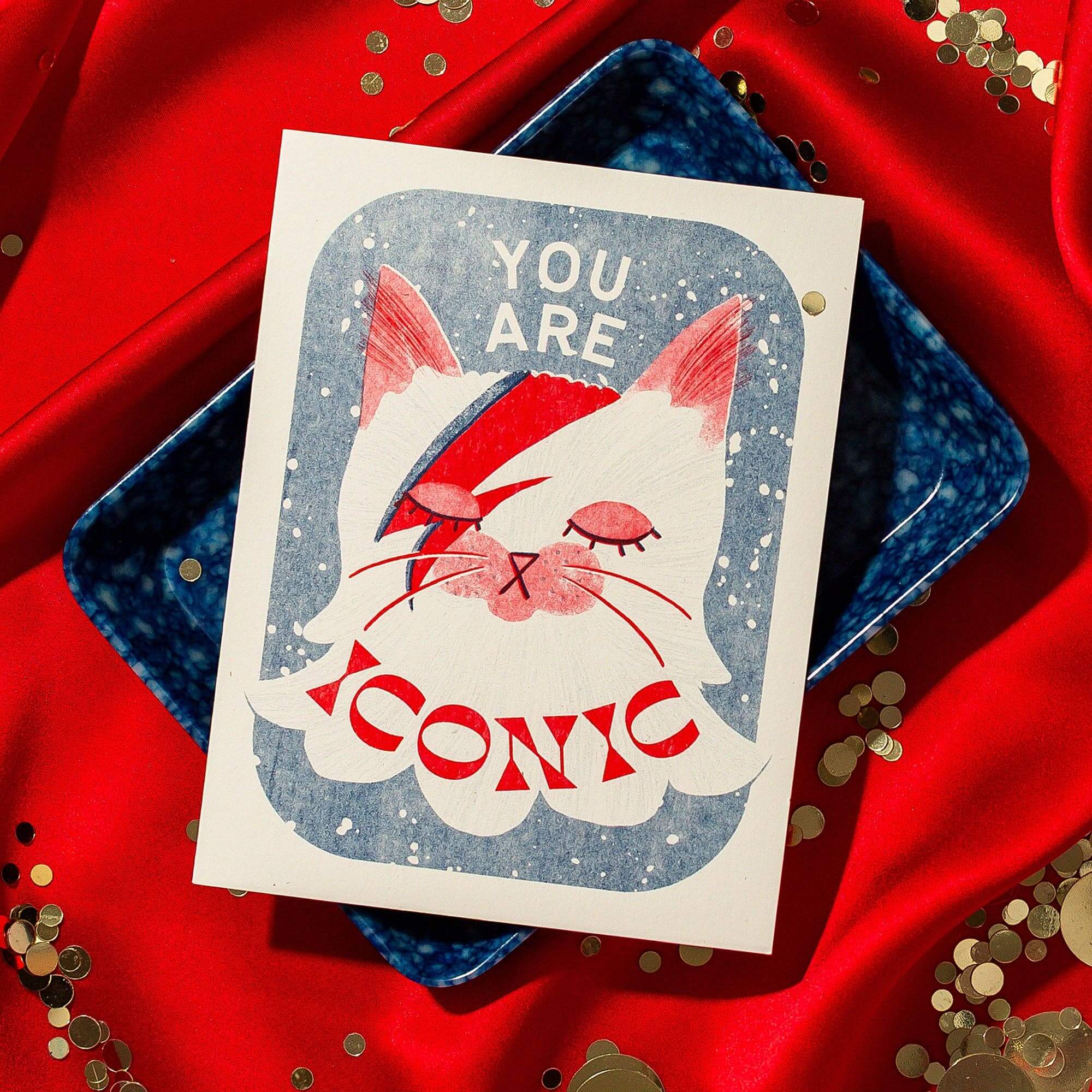 Card with a Bowie inspired cat illustration and text 'You are iconic' on a red background with confetti.