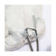 Close-up of white clay with a tool scraping it.