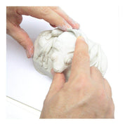 Hands shaping a white clay sculpture of a frog on a white background