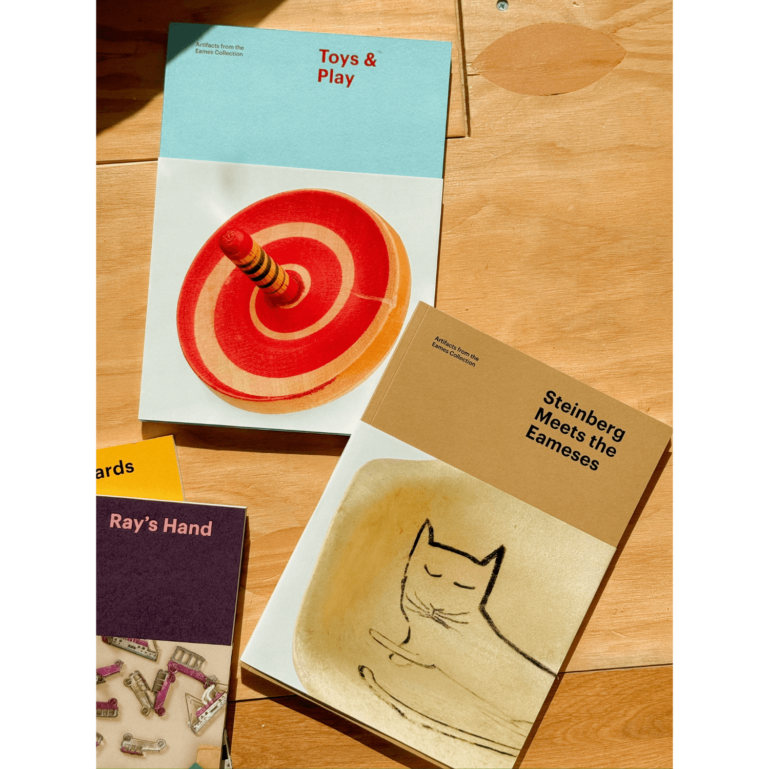 Three books on a wooden surface with titles and illustrations visible