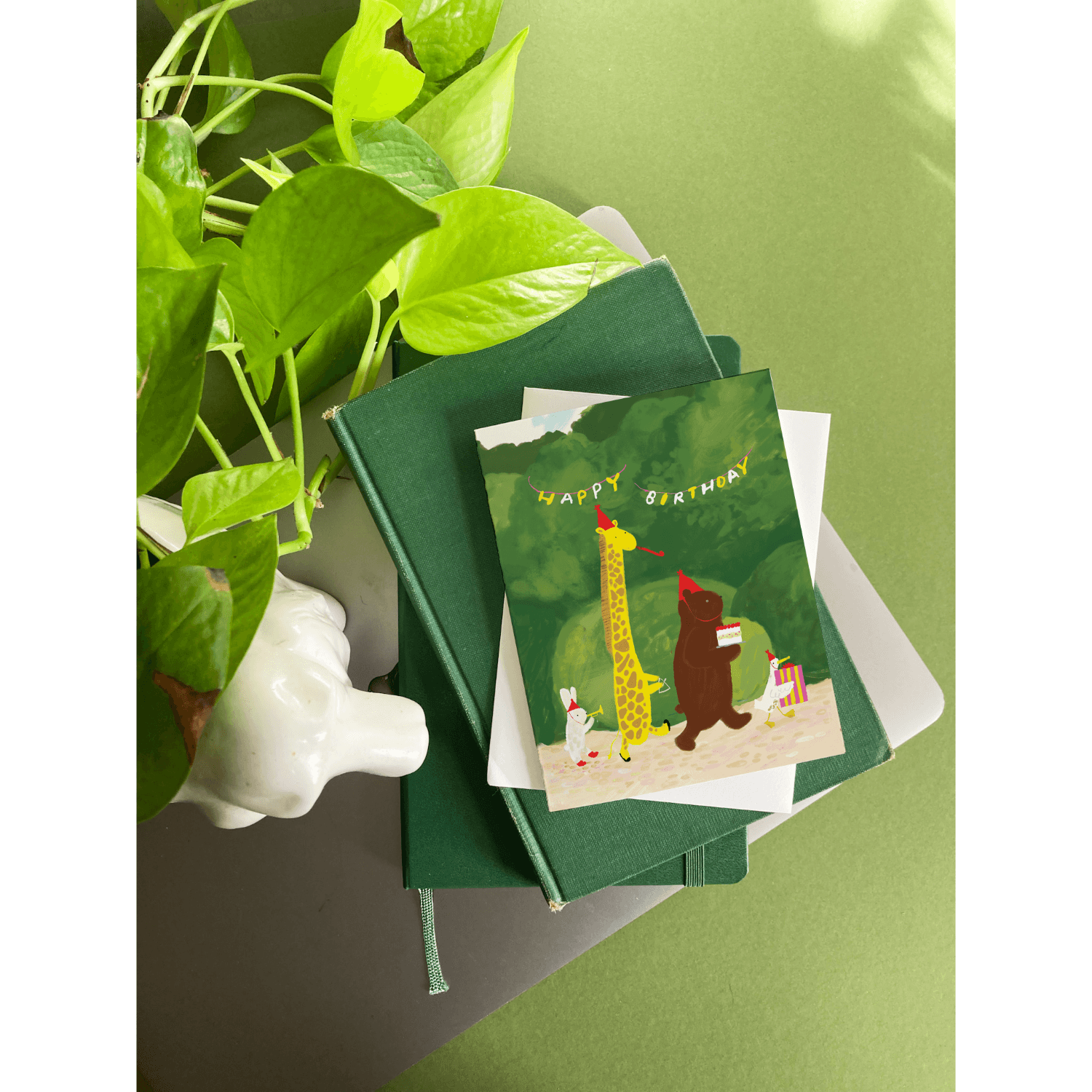 Green birthday card with a giraffe and bear illustration on a green background