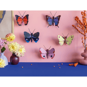 Colorful butterfly decorations on a pink wall with flowers and decorative elements on a blue surface.