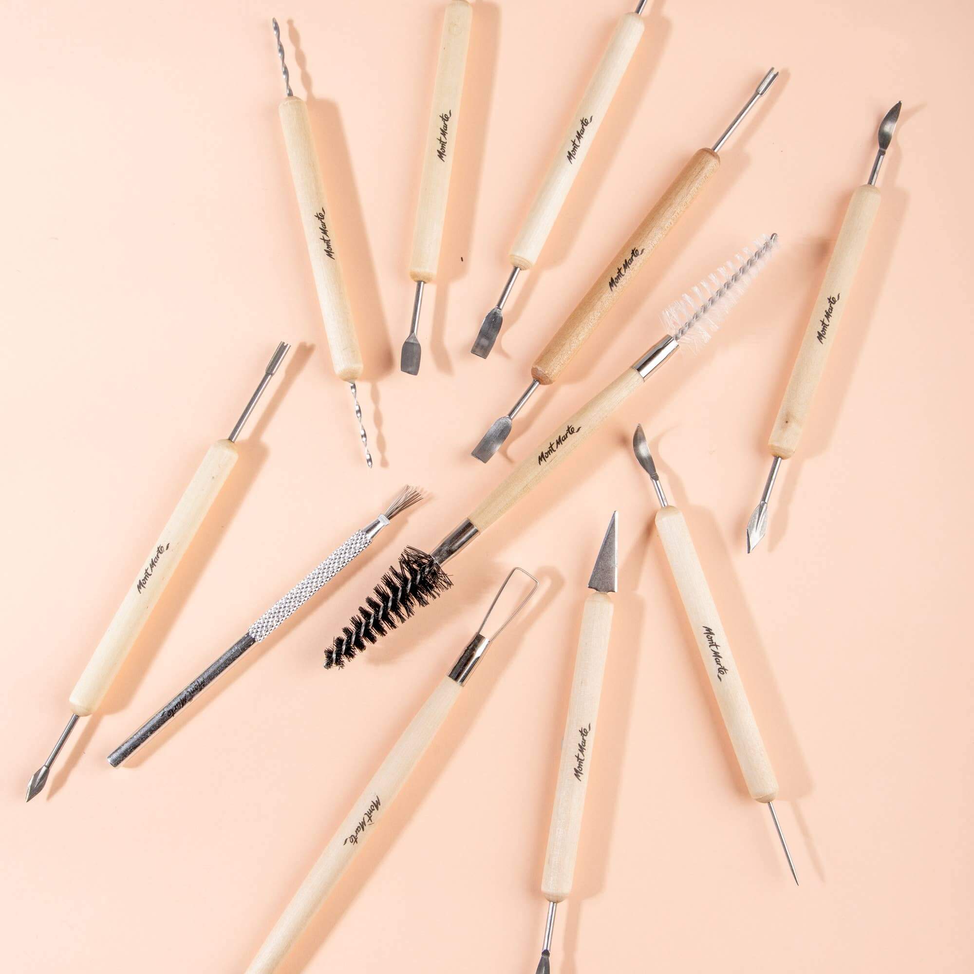 Set of clay tools with wooden handles on a pink background