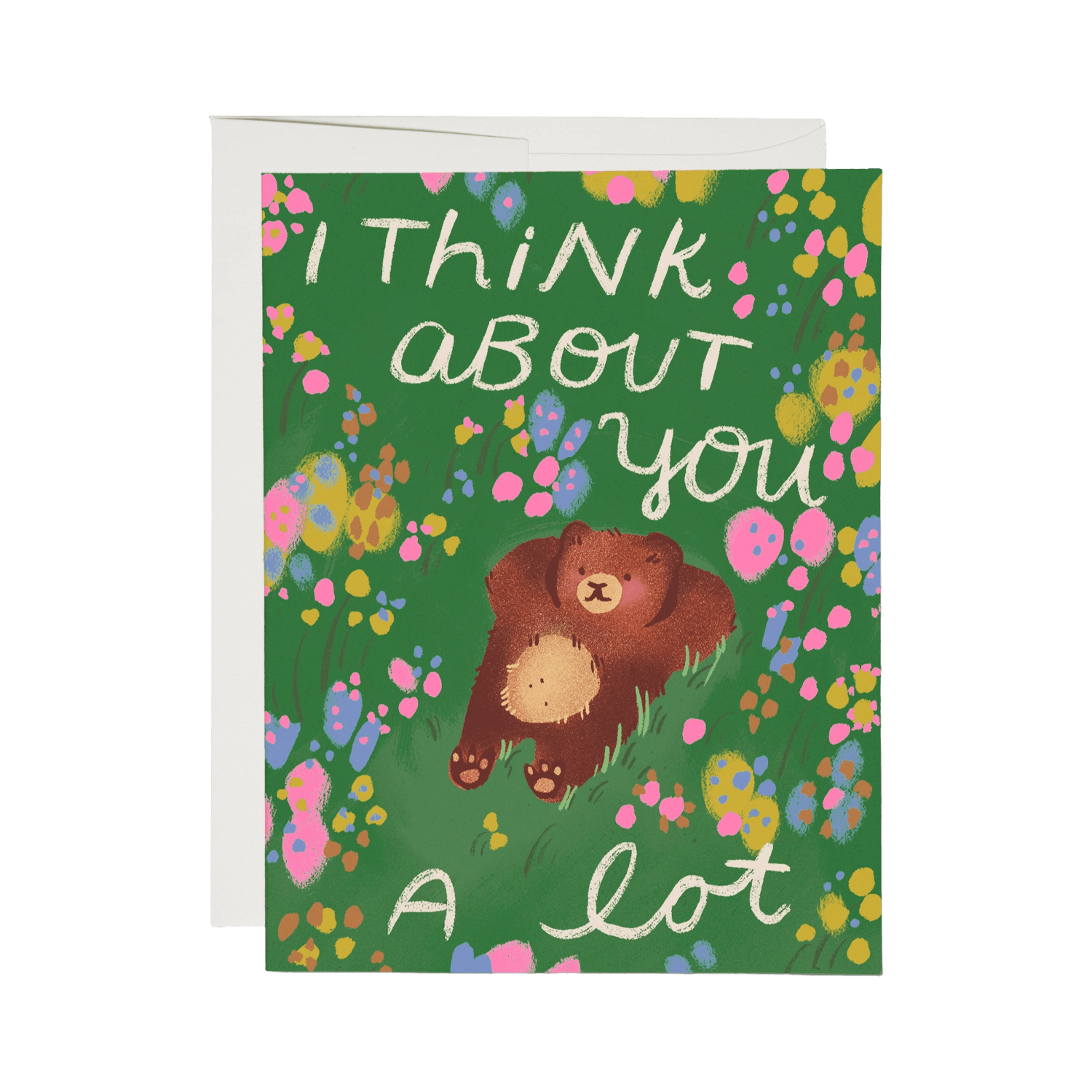 Greeting card with an illustration  of a bear lounging in the grass with flowers all around on a green background