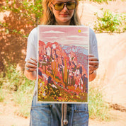 Person holding a colorful landscape print outdoors
