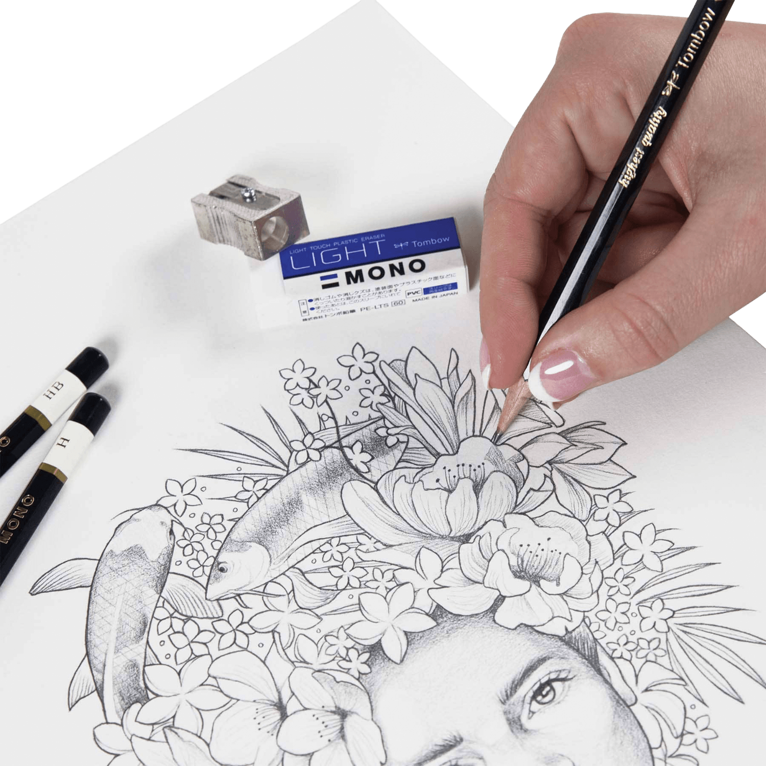 Hand drawing a detailed illustration of a face with flowers and fish using a pencil on a white sheet of paper.