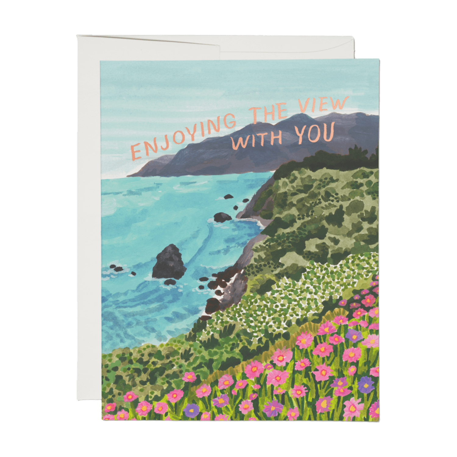 A landscape greeting card featuring an illustrated coastal scene with turquoise water, green cliffs, pink flowers, and the text 'ENJOYING THE VIEW WITH YOU' in peach. A white envelope is partially visible behind the card on a white background.