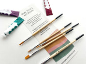 Set of paintbrushes with branded packaging on a white surface