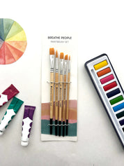 Set of paintbrushes with a color wheel and watercolor pan set on a light background