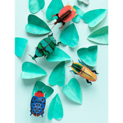 Colorful paper beetles on turquoise leaves against a light blue background