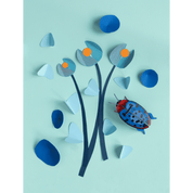 Artistic arrangement of paper flowers and a beetle on a light blue background