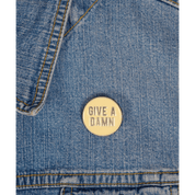 Denim jacket with a beige 'Give a Damn' pin.