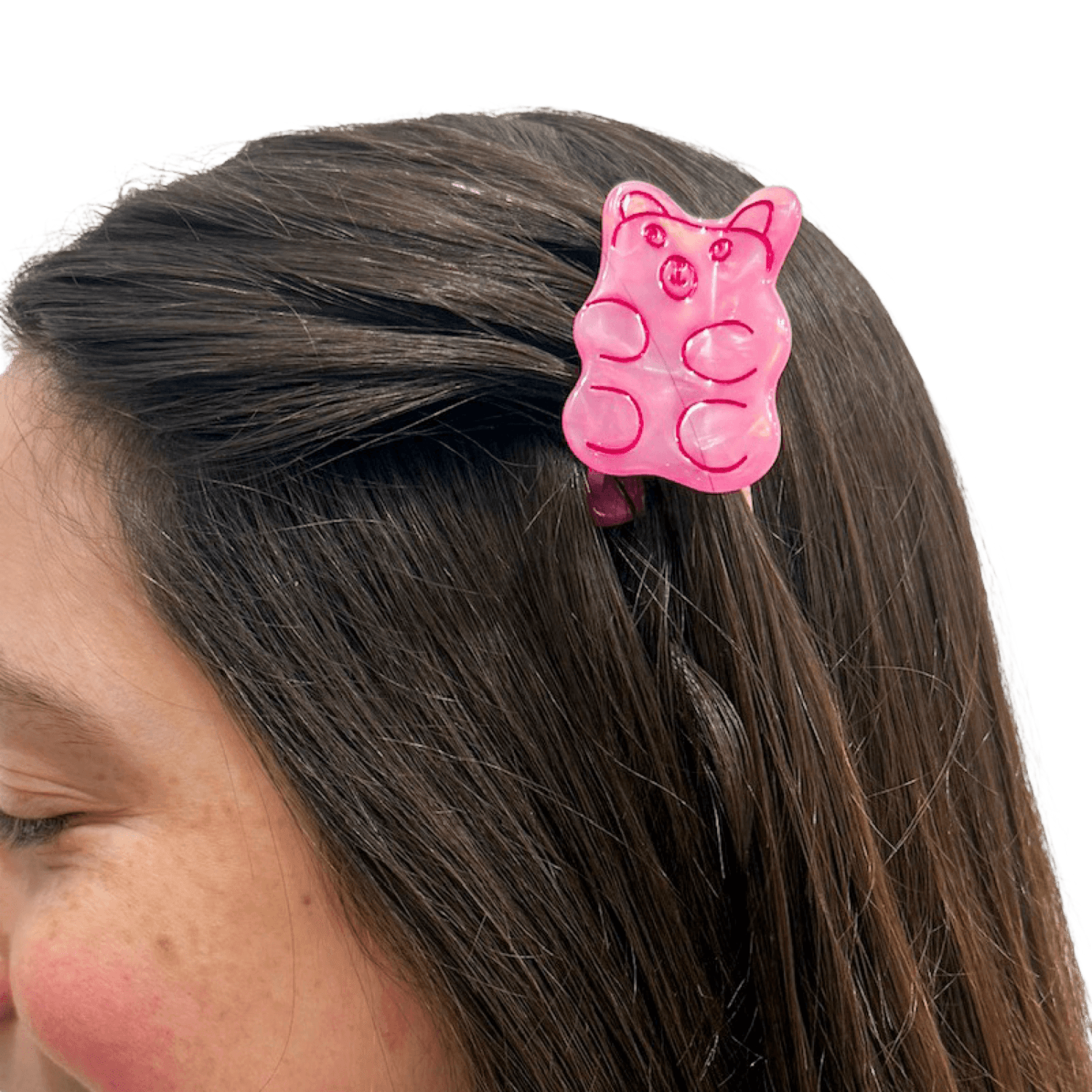 Small pink gummy bear shaped hair clip in a person's hair