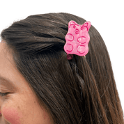 Small pink gummy bear shaped hair clip in a person's hair