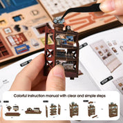 Hand holding a miniature wooden structure with tweezers, next to an instruction manual