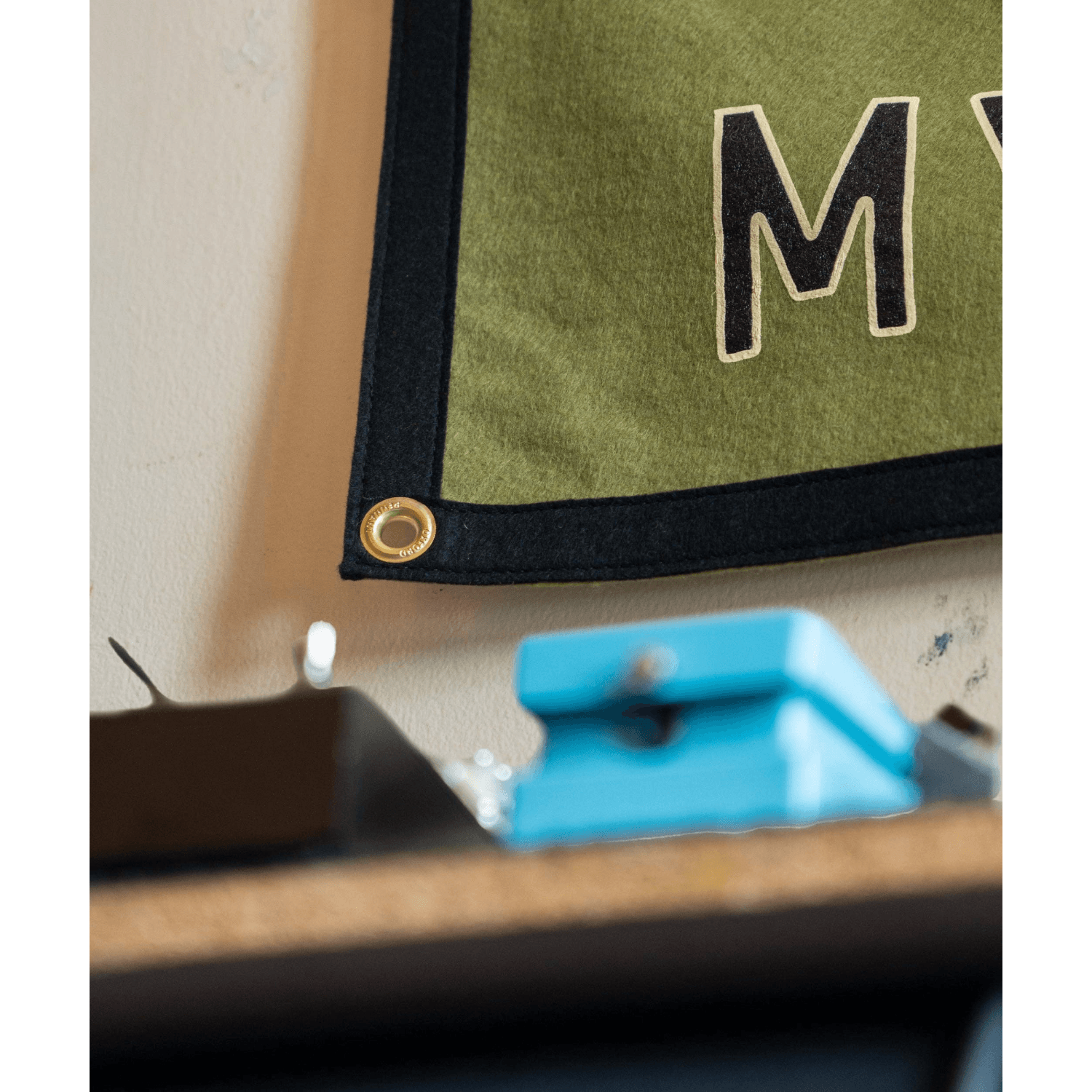 Green fabric with a large 'M' letter on a beige surface