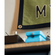 Green fabric with a large 'M' letter on a beige surface