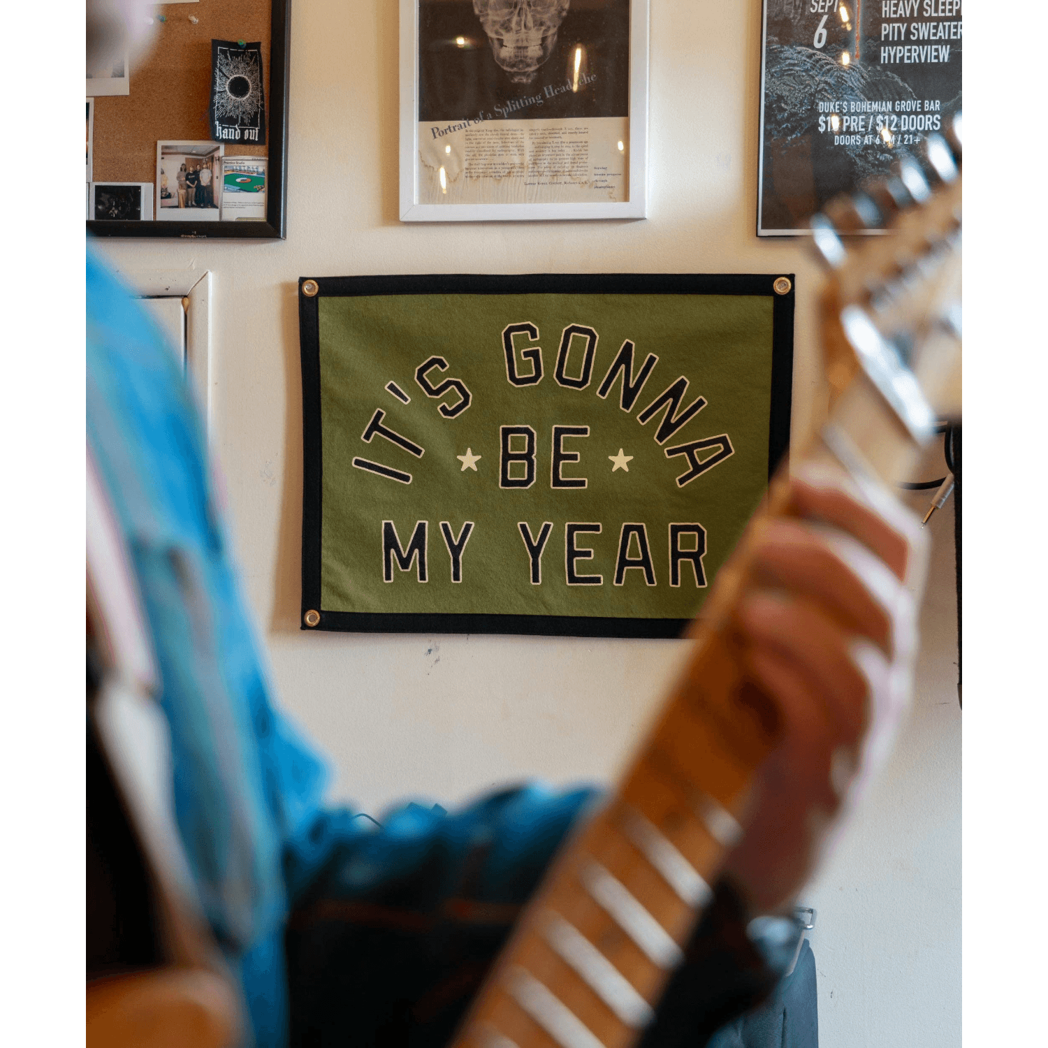 Person playing guitar with a motivational banner on the wall