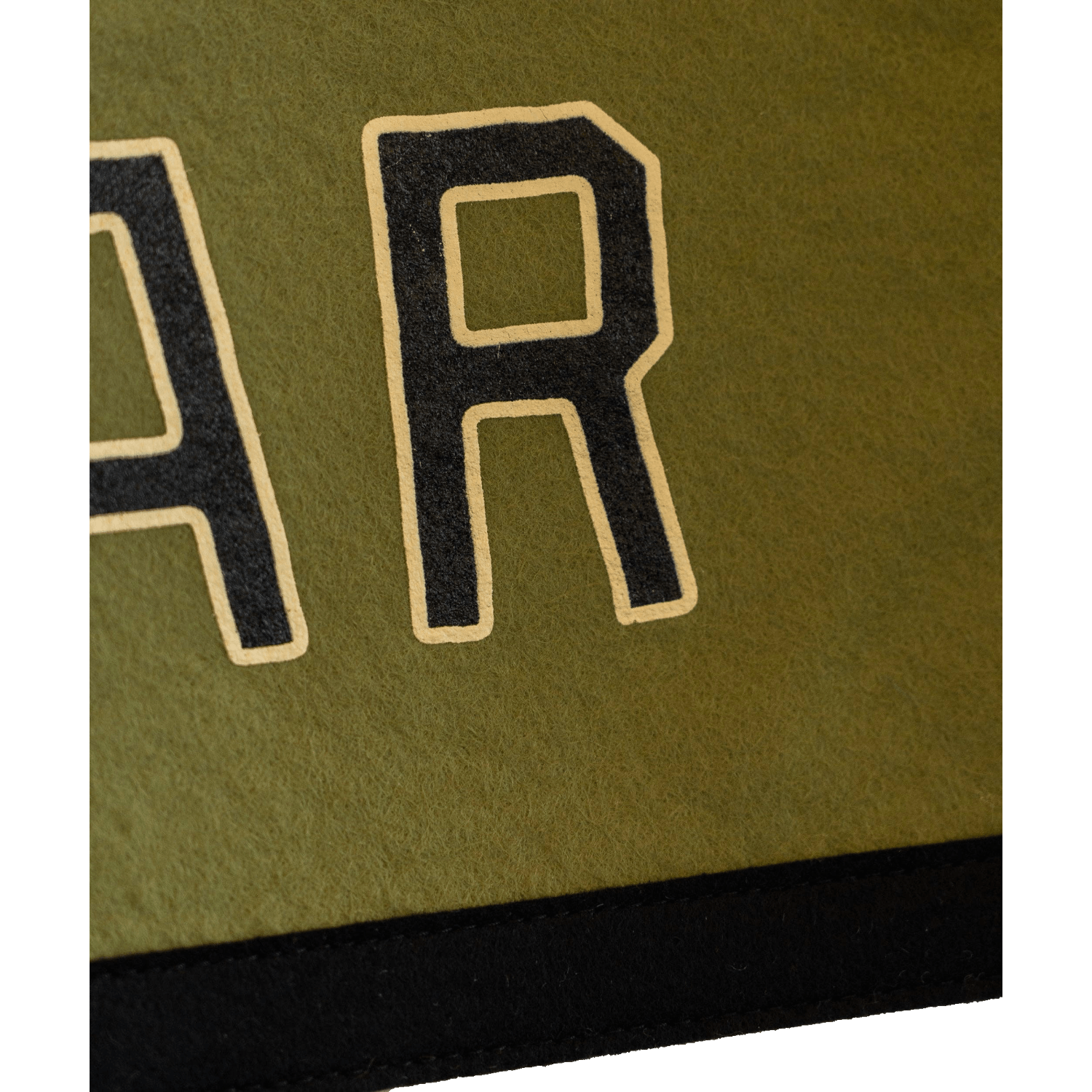 Close-up of a green fabric with black letter 'R' patch