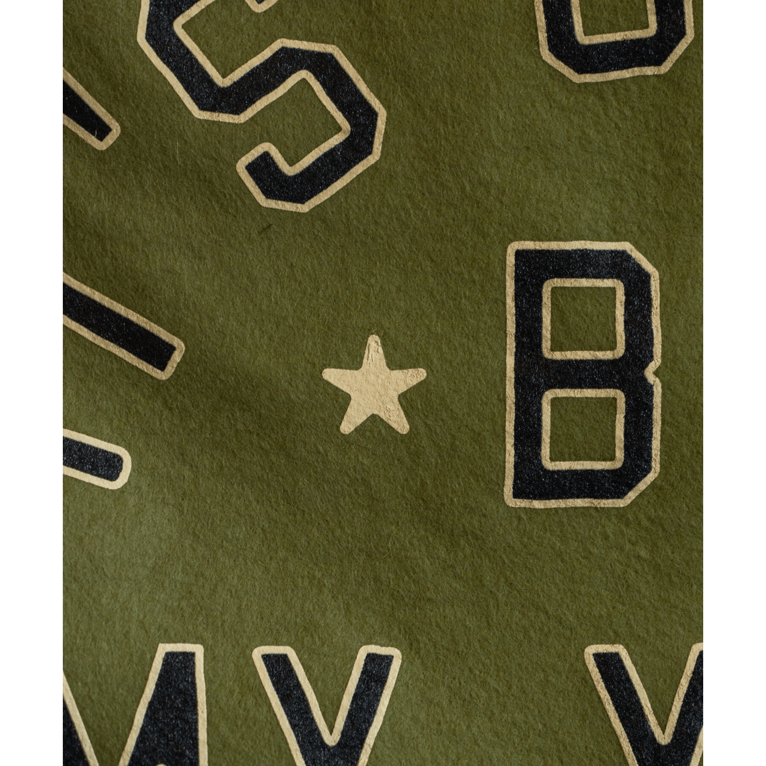 Close-up of a green fabric with black and gold lettering and a star.