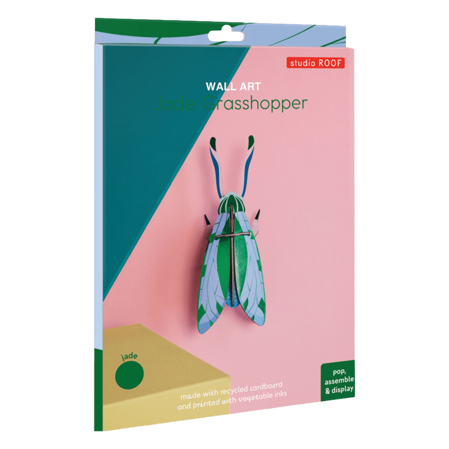 Packaging of a grasshopper wall art with 'studio ROOF' branding on a pink background.