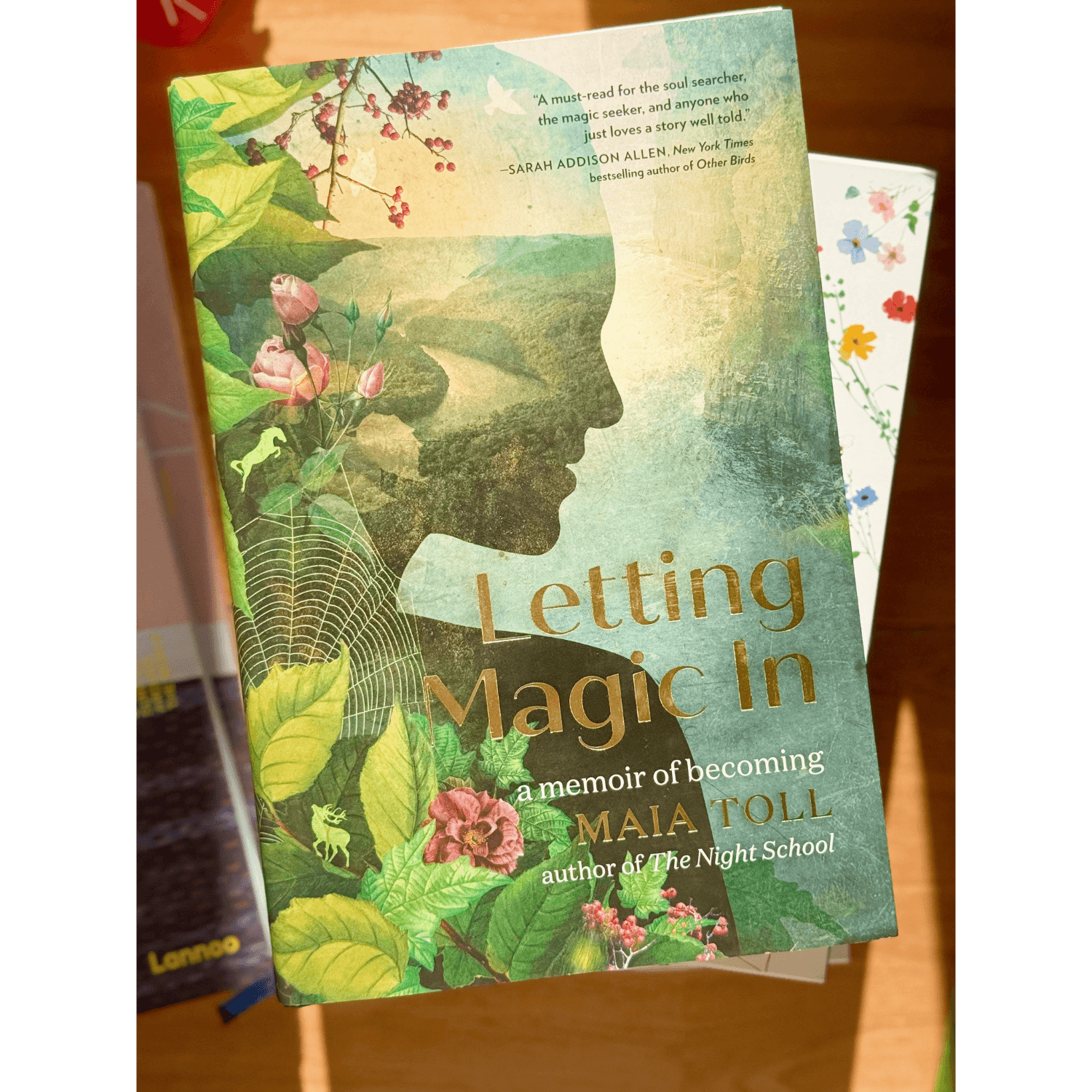 Book titled 'Letting Magic In' by Maia Toll on a wooden surface