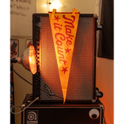 Amplifier with a 'Make it Count' flag on top, surrounded by various items in a room.