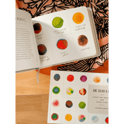 Open book with colorful dot illustrations on a wooden surface