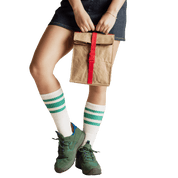 Person holding a brown paper bag with a red strap, wearing green sneakers and white socks with green stripes.