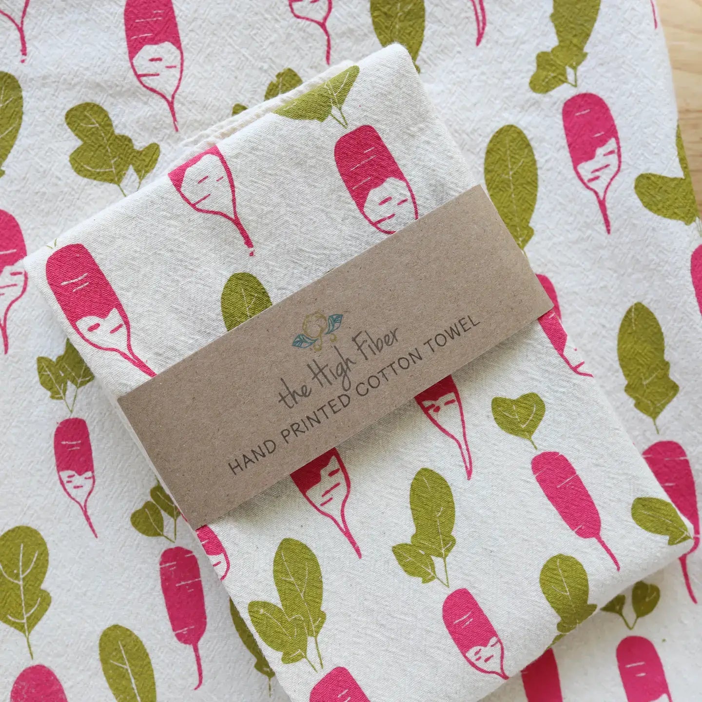 Folded hand printed cotton towel with a label on an unfolded printed cotton towel.