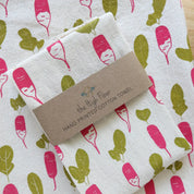 Folded hand printed cotton towel with a label on an unfolded printed cotton towel.