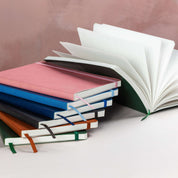 Stack of colorful notebooks with one open on a light background