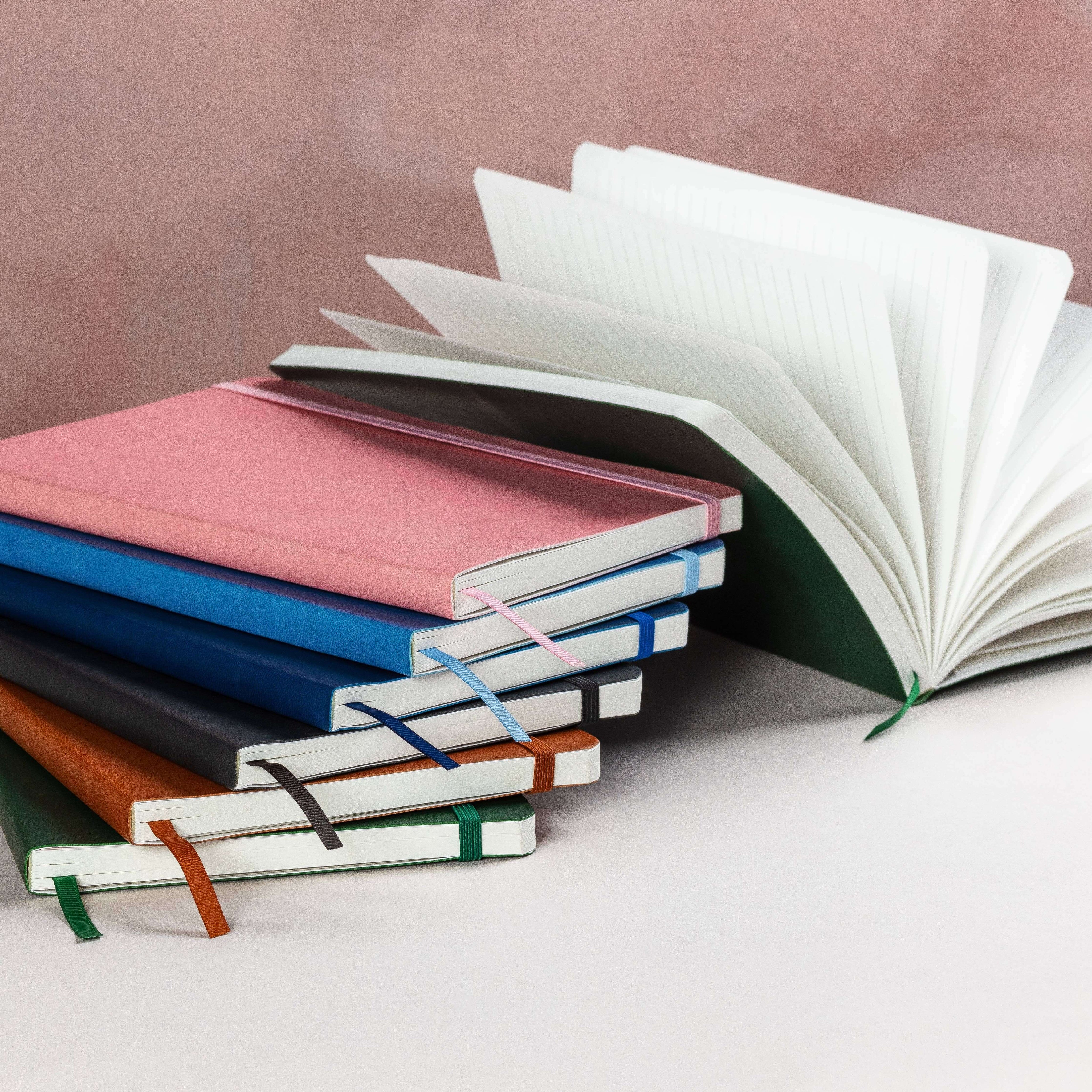 Stack of colorful notebooks with one open on a light background