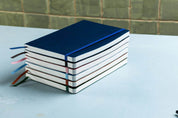 Stack of notebooks with colorful ribbons on a light blue surface